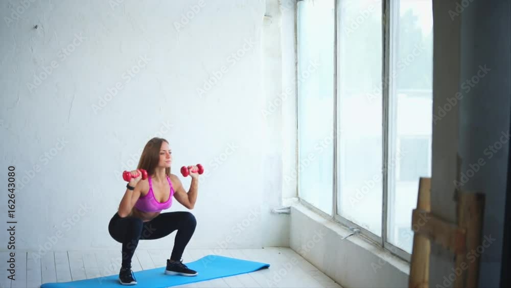 The young and athletic fitness trainer takes deep dips with dumbbells awaiting the development of the gluteal muscles and strengthening the back in the fitness club. The young and athletic fitness trainer takes deep dips with dumbbells awaiting the development of the gluteal muscles and strengthening the back in the fitness club.