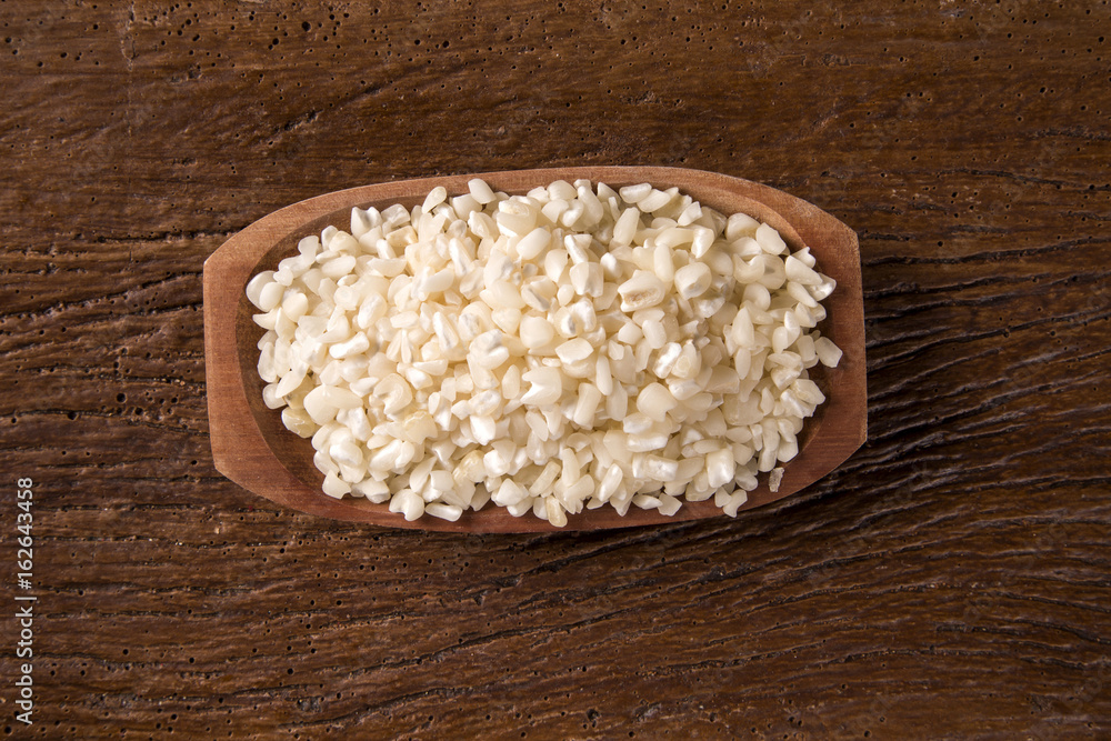 White grated corn kernels in wooden bowl. canjica / mungunza White grated corn kernels in wooden bowl. canjica / mungunza