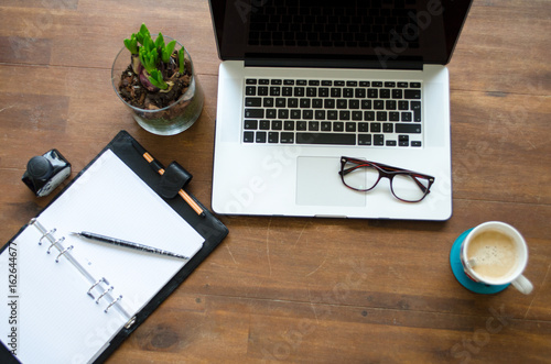 Top view of a laptop on a table with coffee and glasses