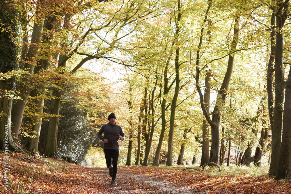 Mature Man Running Through Autumn Woodland Mature Man Running Through Autumn Woodland