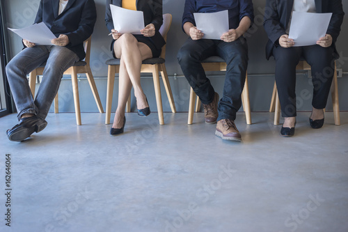 Group of peoples are sitting to review the documents while waiting for a job interview.