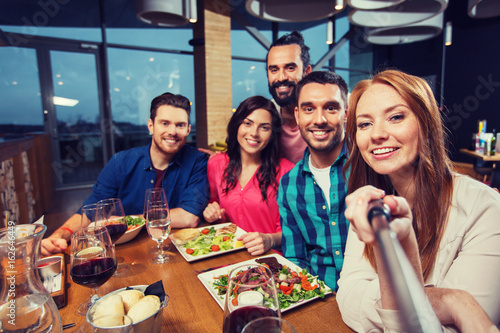 friends picturing by selfie stick at restaurant