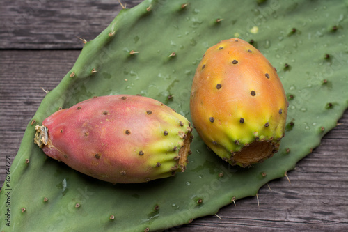 Fresh ripe whole prickly pears a leaf of the plant on wooden vintage background