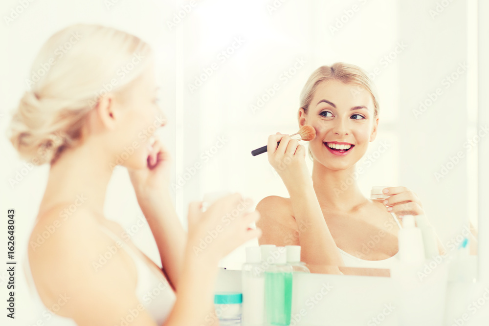 woman with makeup brush and powder at bathroom