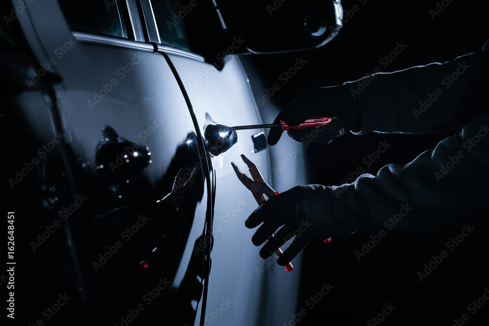 Car thief using a tool to break into a car Stock Photo Adobe Stock