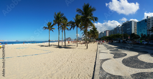 View of Copacabana beach with its famous mosaic on the boardwalk and coconut trees in summer day photo