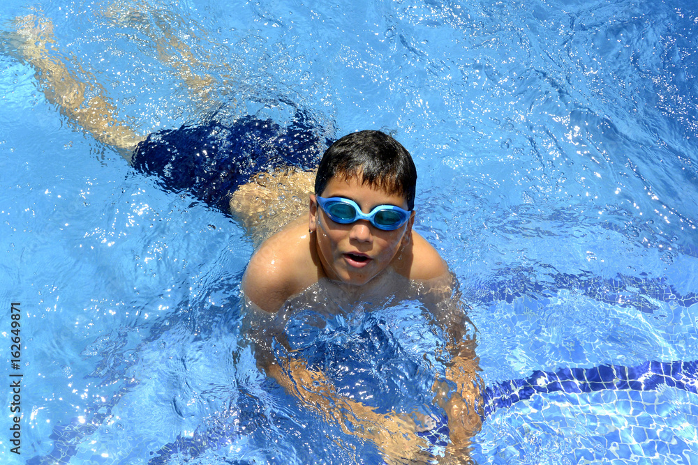 Swimming is fun!!! A boy is in swimming pool with goggles