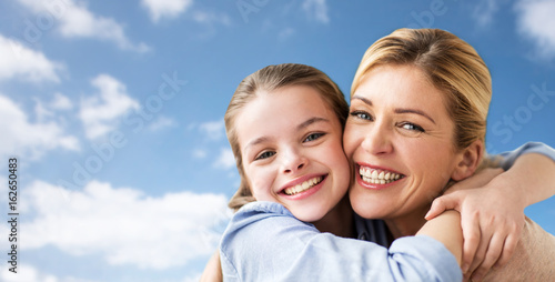 happy family of girl and mother hugging over sky