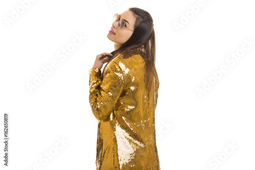 Cheerful stylish young girl in golden jacket and round sunglasses