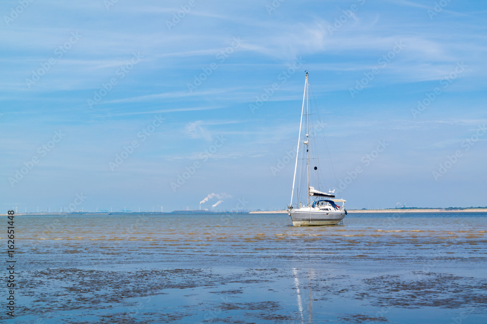 Fototapeta premium Sailboat aground on sandflat at low tide near Rotterdam, Netherlands