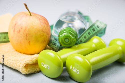 Dumbbells, an apple, a towel and a bottle of water