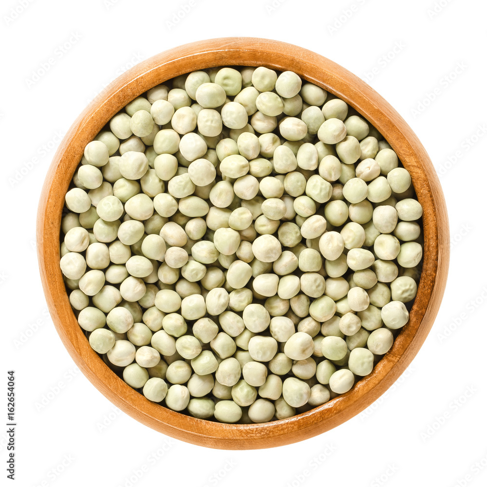 Dried green peas in wooden bowl. Small light green spherical seeds from the pods of Pisum sativum, used as vegetable or for sowing. Isolated macro photo closeup from above on white background. Dried green peas in wooden bowl. Small light green spherical seeds from the pods of Pisum sativum, used as vegetable or for sowing. Isolated macro photo closeup from above on white background.