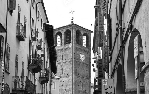 A ancient belfry between old buildings in Pinerolo, Italy. Black and white.