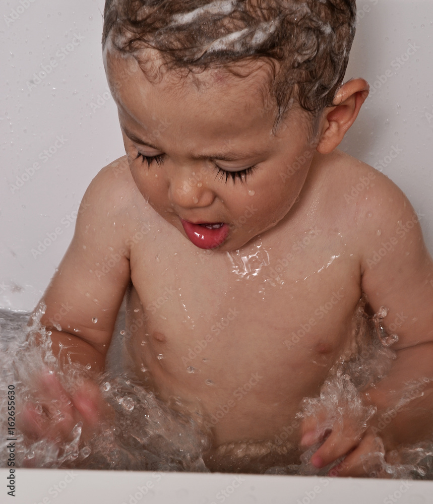 Retrato de un niño en la bañera con shampu, jabón en la cabeza
