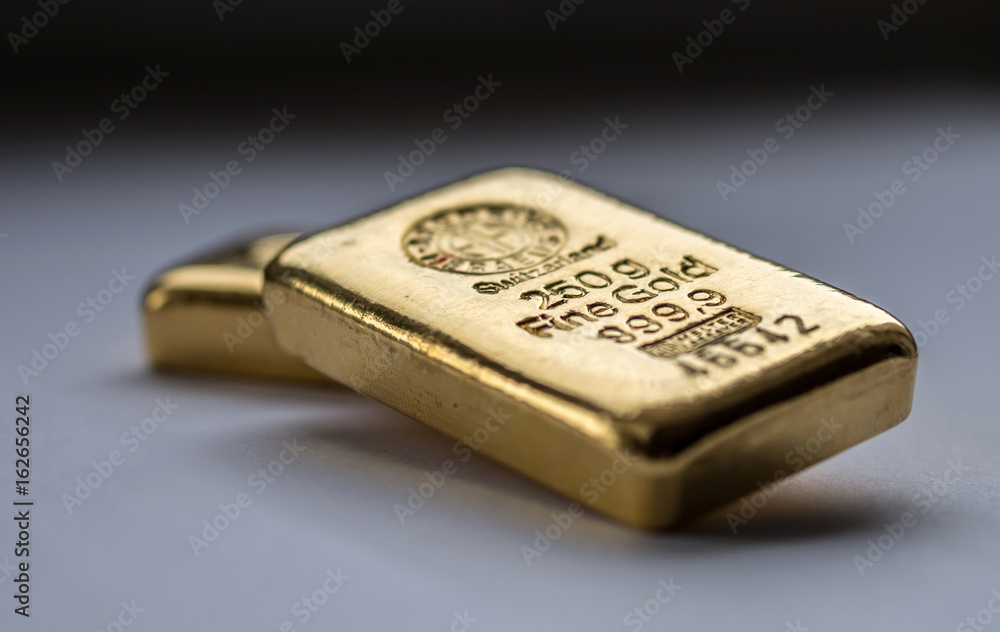 Two cast gold bars on a grey background. Selective focus. Two cast gold bars on a grey background. Selective focus.