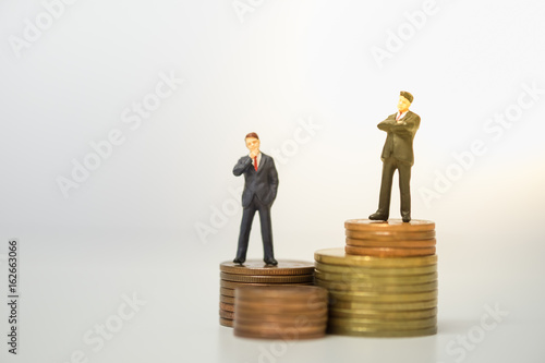 Business and competition Concept. Two businessman miniature figures standing on top of stack of coins to thinking and planning.