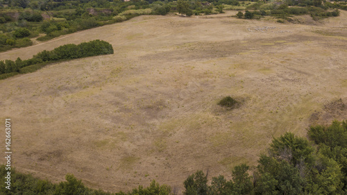 Vista su un paesaggio bucolico con un vasto campo incoltivato dove nasce spontanemente qua e là qualche cespuglio photo