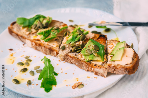 toasted rye bread with sliced avocado and herbs, simple rustic sandwich