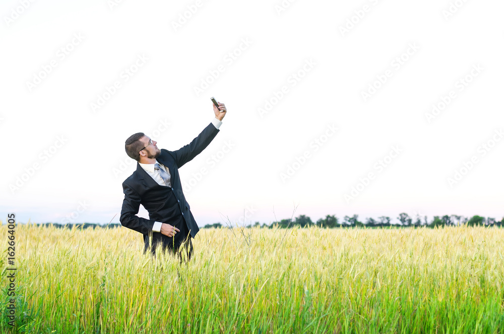 Businessman with a smartphone in a wheat field, a copy of the free space. Businessman with a smartphone in a wheat field, a copy of the free space.