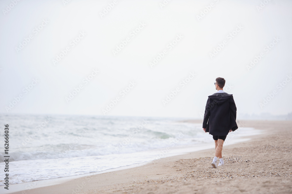 Young fashionable man walking along the beach Young fashionable man walking along the beach