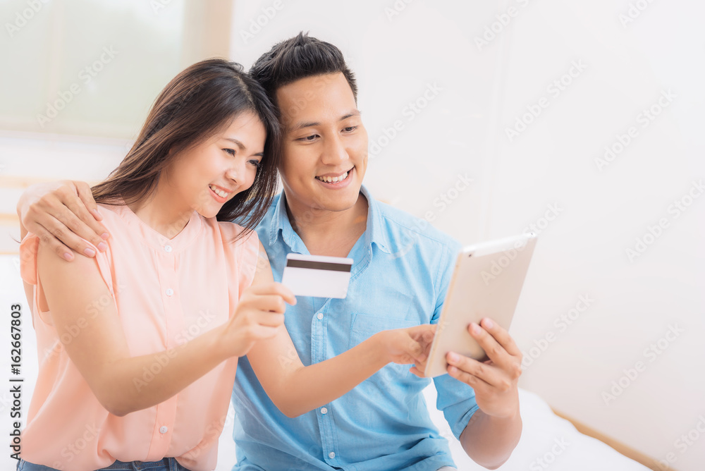 Happy Asian couple using tablet and credit card for online shopping Happy Asian couple using tablet and credit card for online shopping