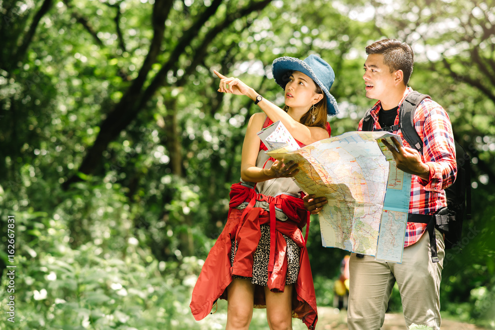 Asian couple in forest checking a map for directions