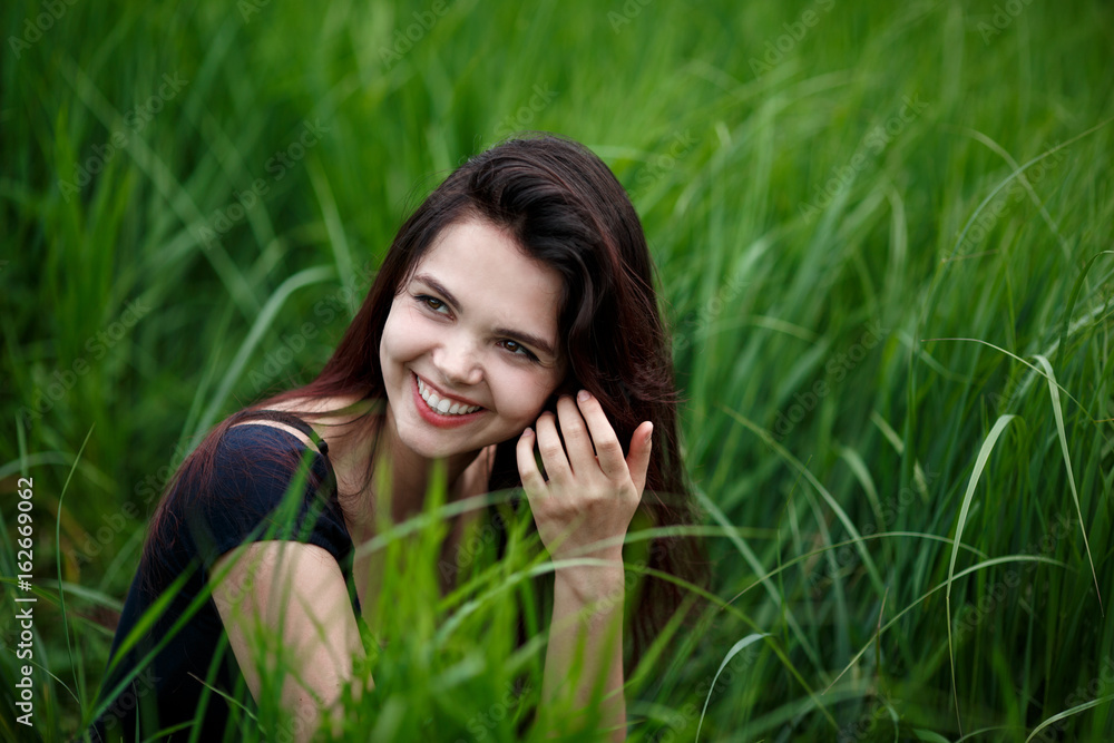 Beautiful woman on the grass. Woman relaxing outdoors looking happy and smiling Beautiful woman on the grass. Woman relaxing outdoors looking happy and smiling