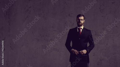 Businessman standing over dark wall background. Business, career job concept.