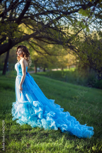 Young beautiful girl in a lush blue dress