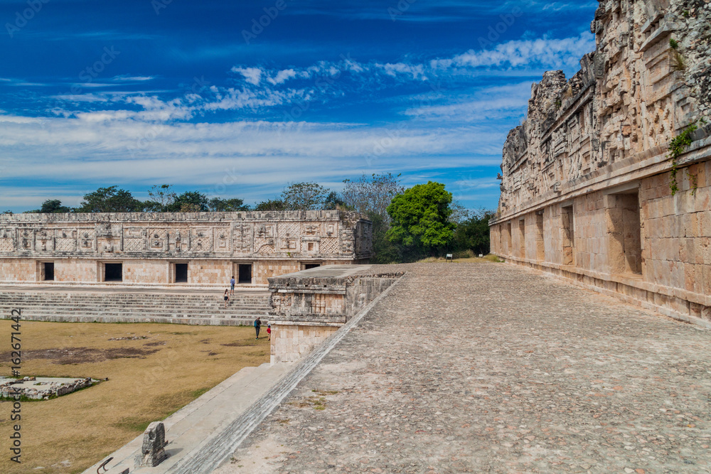 UXMAL, MEXICO - FEB 28, 2016: Tourists at the courtyard of the Nun's Quadrangle (Cuadrangulo de las Monjas) building complex at the ruins of the ancient Mayan city Uxmal, Mexico