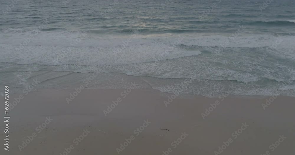 Aerial view of sunset over beautiful sea and cloudy sunset sky background. Sea waves crashing on shore of sandy beach - video in slow motion Aerial view of sunset over beautiful sea and cloudy sunset sky background. Sea waves crashing on shore of sandy beach - video in slow motion