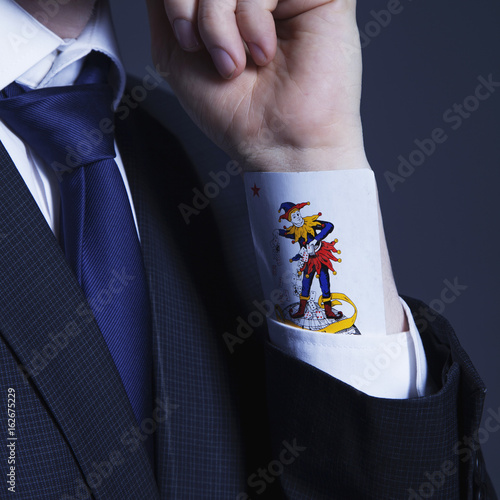 Fotografija A partial view of a businessman with a Joker card in a sleeve as symbol of cheat