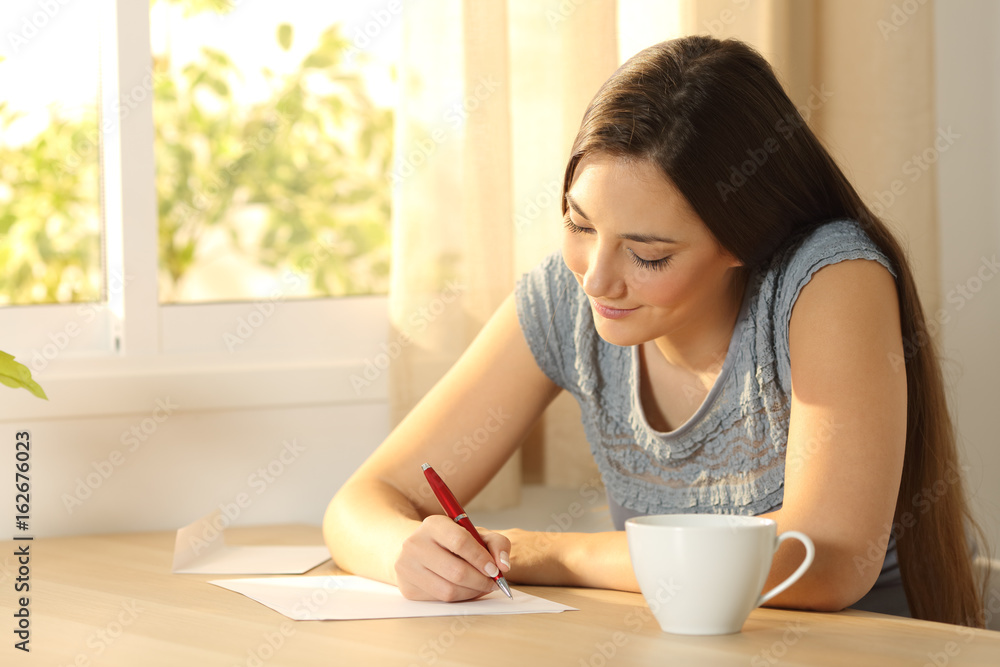 Girl writing a letter on a table Girl writing a letter on a table