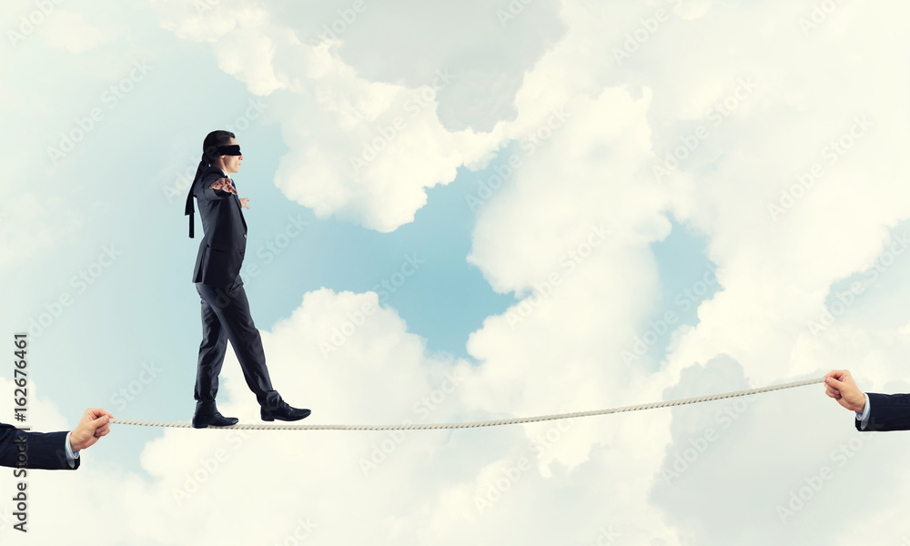 Business concept of risk support and assistance with man balancing on rope Business concept of risk support and assistance with man balancing on rope
