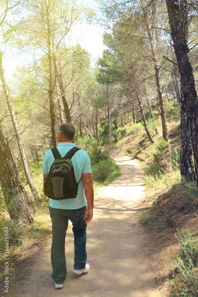 Mature man hiking through the forest at the beginning of Caminito del Rey, Malaga, Spain Mature man hiking through the forest at the beginning of Caminito del Rey, Malaga, Spain