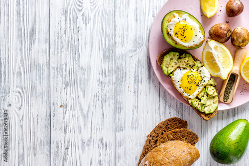 Healthy food concept. Sandwiches for breakfast with avocado and fried eggs on wooden table background top view copyspace