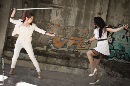Two businesswomen are fighting at swords. © Demian