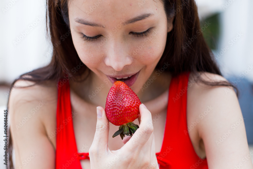 Smiling woman eating a fresh strawberry
Smiling woman eating a fresh strawberry