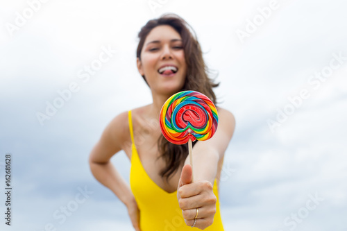 Happy young woman posing with lollipops at the beach in summertime © baconstudiony