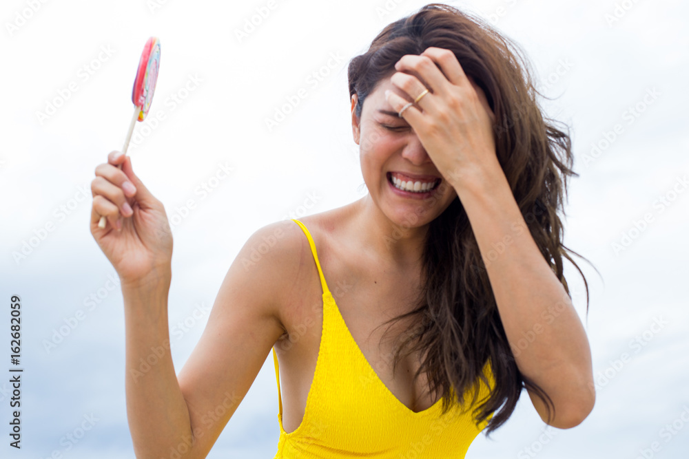 Happy young woman posing with lollipops at the beach in summertime Happy young woman posing with lollipops at the beach in summertime