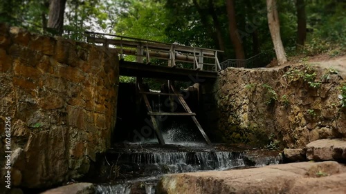 Old wooden water gateway with chain drive cascade on lake drain glide cam