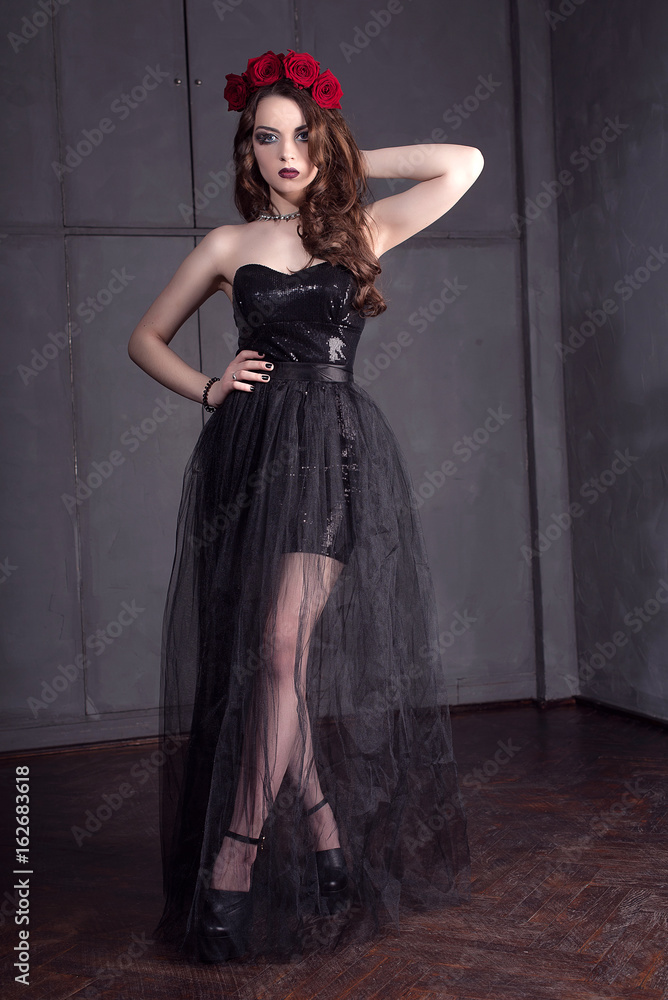 beautiful young woman with roses flower in hair, wearing black dress with make-up over dark background, gothic atmosphere. dark red lips.close-up fashion retouched portrait