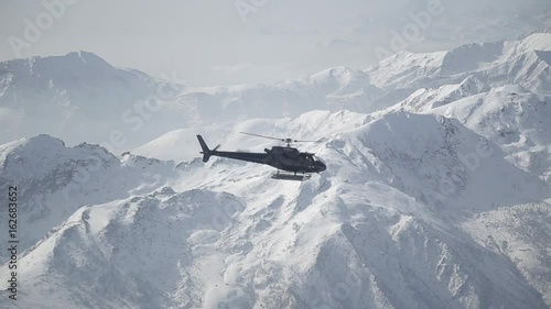 the helicopter is flying high the snowy mountains