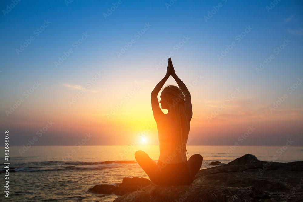 Meditation woman yoga silhouette on the Sea beach during amazing sunset. Healthy lifestyle.