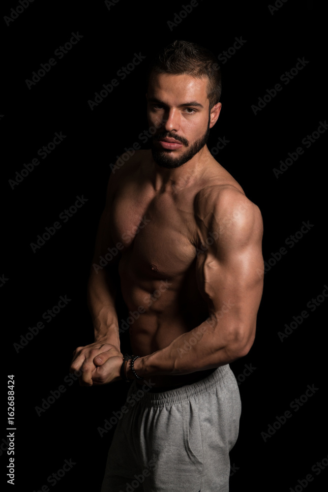 Muscular Man Flexing Muscles On Black Background