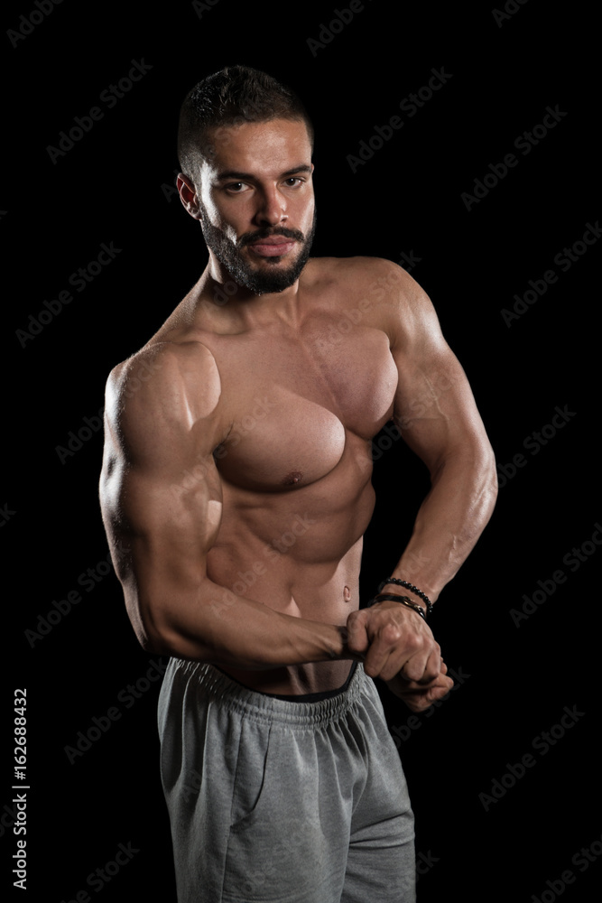 Muscular Athlete Flexing Muscles On Black Background