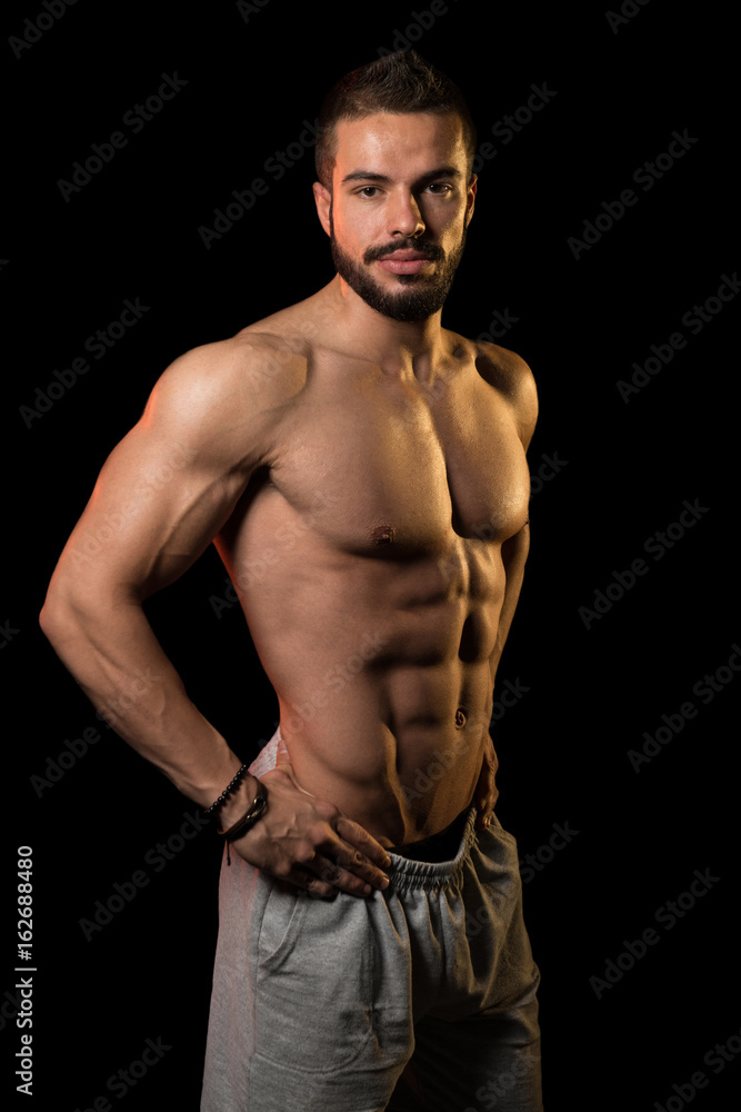 Muscular Athlete Flexing Muscles On Black Background