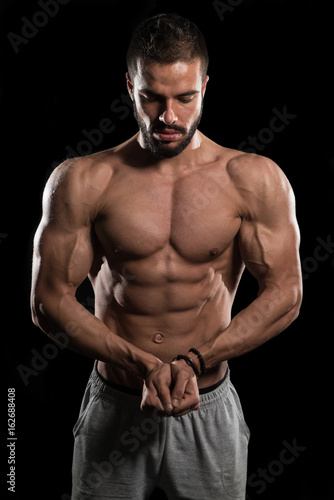 Muscular Model Flexing Muscles On Black Background