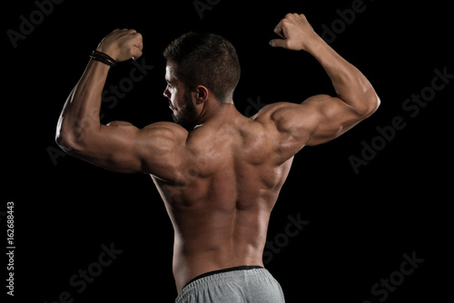 Muscular Athlete Flexing Muscles On Black Background © Jale Ibrak