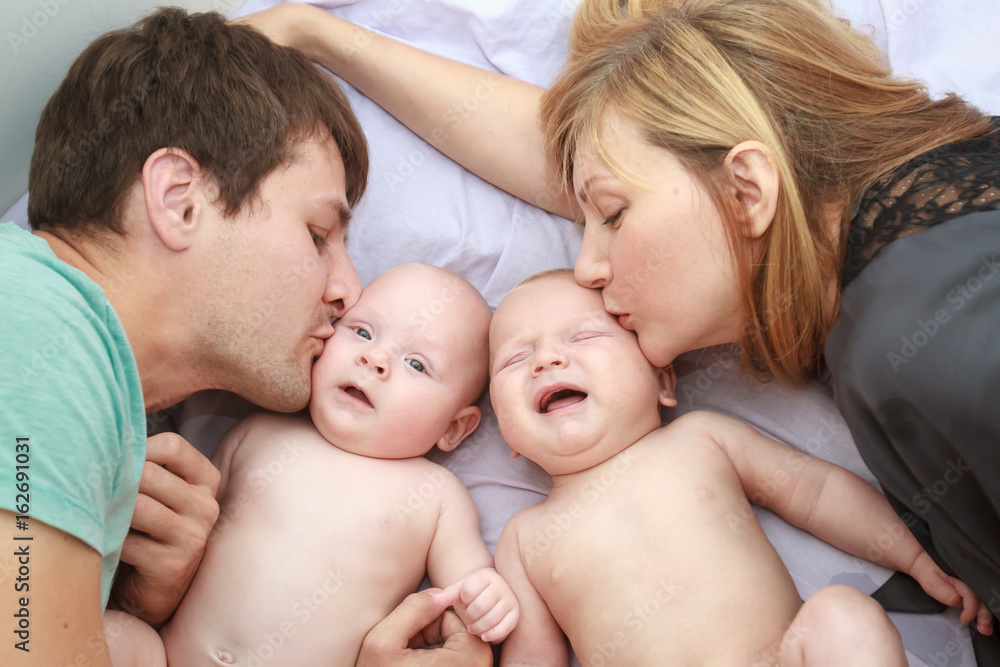 indoor portrait of young beautiful mother and father with baby, family with twins at home